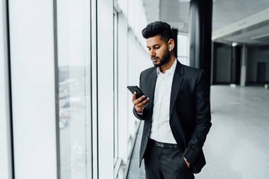 Modern telefonunu, internet iletişimini, modern Hintli iş adamının gülümseyen genç bir Hintli portresi..