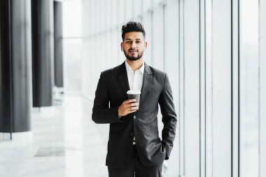 Modern ofis binasında elinde kahveyle yakışıklı, sakallı Hintli bir adam. Şirket müdürü, patron, yatırım..