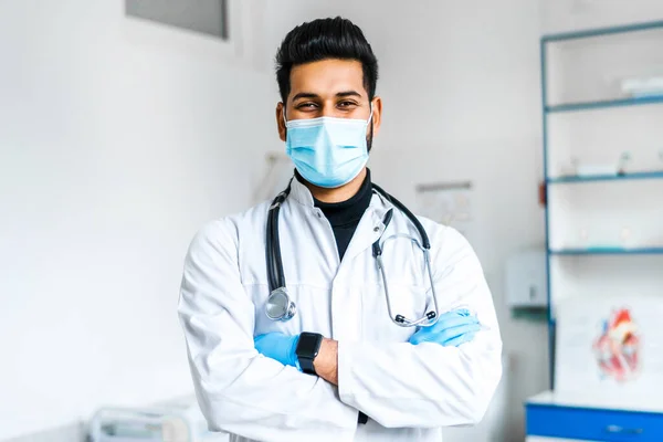 A young Indian doctor in a protective mask and gloves with a stethoscope on among a modern hospital, Indian medicine, health and self-care.