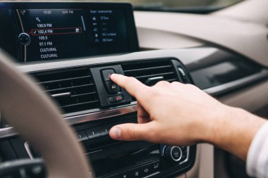Close up of hand reaching for button in modern car.