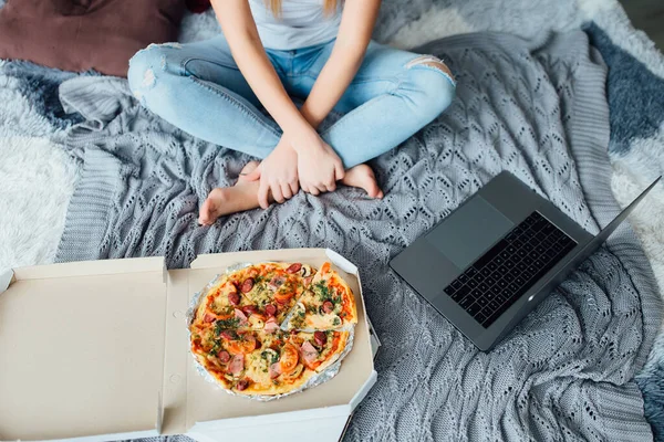 Close up foto ragazza con la pizza, donna seduta su un letto. Fotografia Stock