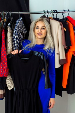 Gülümseyen ve clothin içinde bir elbise seçme genç yetişkin sarışın kadın