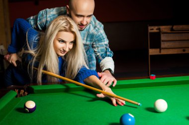 Handsome couple plays billiard on the pool table