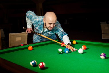 Handsome male model plays at pool billiard table