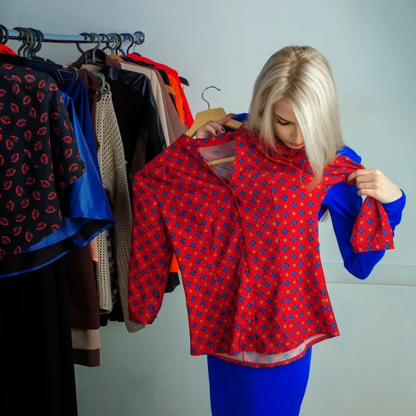 Молодая блондинка выбирает рубашку в магазине одежды — стоковое фото