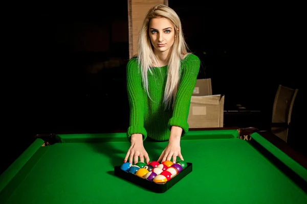 Charming young blonde puts balls in triangle on pool table — Zdjęcie stockowe