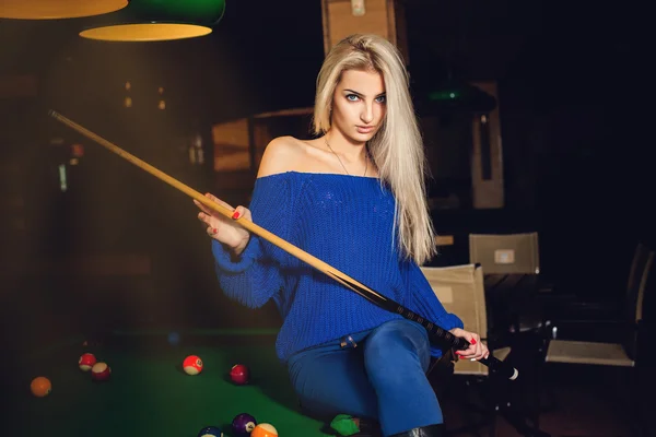 Fashion model posing on pool table with cue in hands — Stock Photo, Image