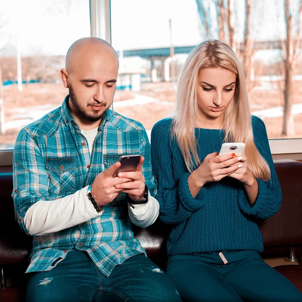 Modernes lebenslustiges Paar gibt Mobiltelefone weiter — Stockfoto