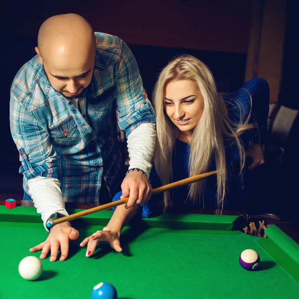 Square portrait of beautiful couple plays billiard on the pool t — Stock Photo, Image