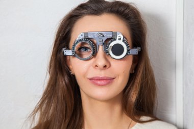 beautiful girl checks vision in an ophthalmologist with correcti clipart
