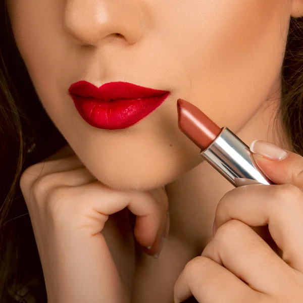 Foto da vicino delle labbra della donna con il rossetto in mano — Foto Stock