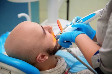 Diş ofisinde ki adamın portresi dişleri tedavi ediyor