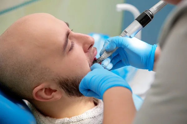 Um homem no dentista trata os dentes — Fotografia de Stock