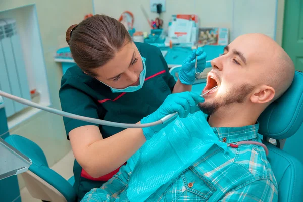 Γοητευτικό κορίτσι οδοντίατρος ελέγχει τα δόντια του ασθενούς της — Φωτογραφία Αρχείου