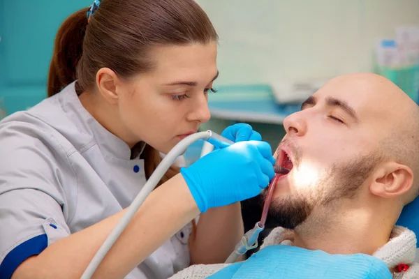 Dentista curando a un paciente masculino — Foto de Stock