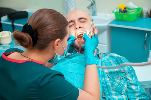 Dentista inserta al tipo de la prótesis en el consultorio dental — Foto de Stock