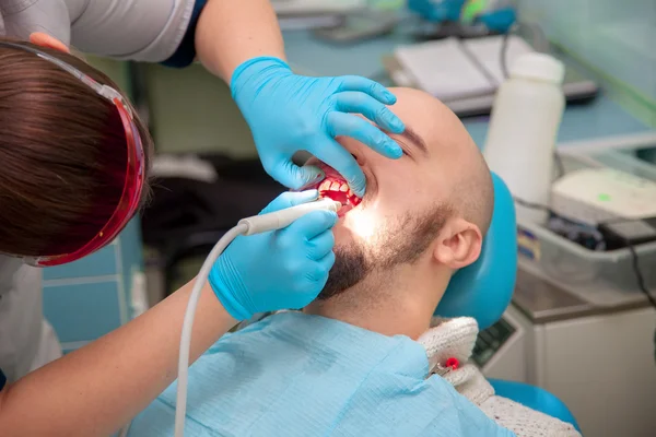 Adam diş hekimi bir resepsiyonda bir plaket temizler — Stok fotoğraf