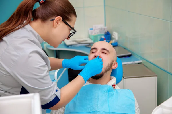 Diş ofisinde adam dişleri kontrol eder — Stok fotoğraf