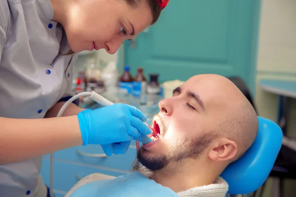 Chico guapo trata dientes de caries en el consultorio dental — Foto de Stock