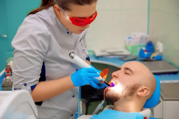 Buen tipo trata los dientes de caries en el consultorio dental — Foto de Stock