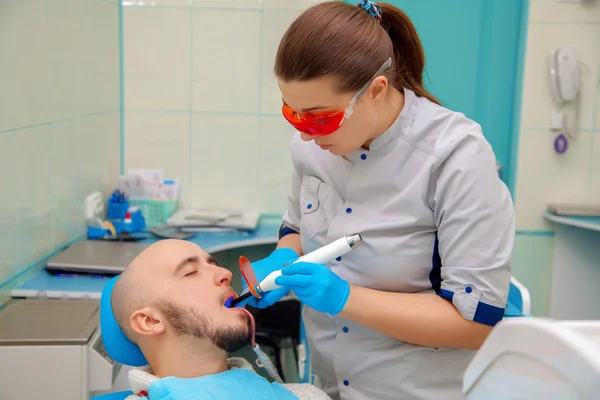 On survey at the dentist checks the teeth of the patient — Stok fotoğraf