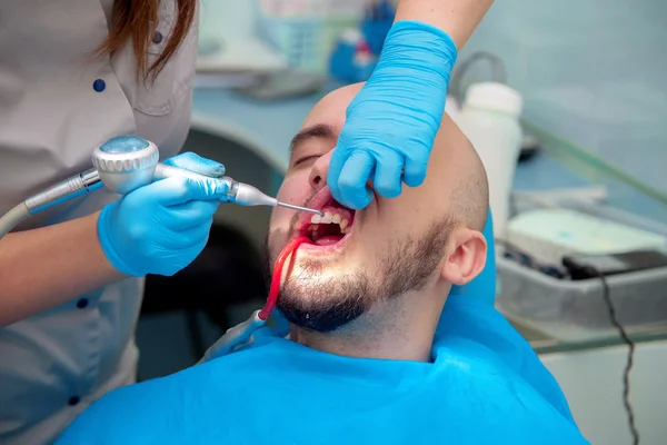 Nice young guy treats his teeth in a dental office at the doctor — Zdjęcie stockowe