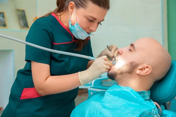 Pretty woman dentist treats the teeth of her patient — Stok fotoğraf