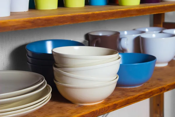 Multicolored plates and cups stand on a shelf — Stock Photo, Image