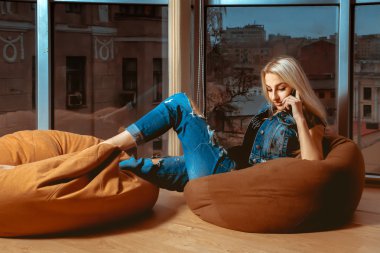 Telefonu konuşurken ve turuncu kanepe n üzerinde poz muhteşem genç sarışın