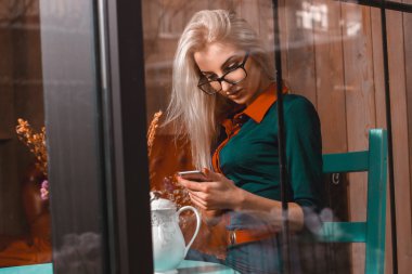 bir kafede bir akıllı telefon kullanan yakışıklı güzel kadın