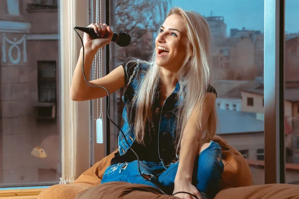 Belle jeune femme blonde chantant karaoké avec un microphone — Photo