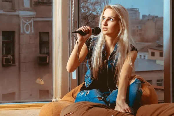 Belle jeune fille blonde chantant karaoké avec microphone et regardant — Photo