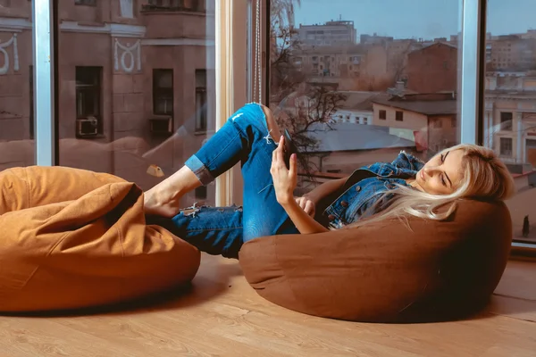 İnce genç sarışın koltukta yalan ve cep telefonunu yazarak