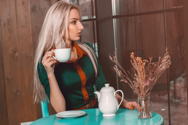 Preciosa chica rubia joven beber café y mirando hacia el wi — Foto de Stock