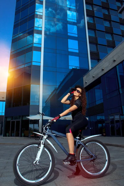 Morena mujer deportiva en gafas de sol posando en bicicleta — Foto de Stock