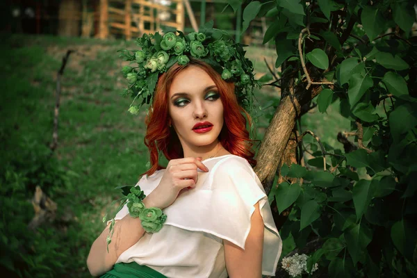 Donna seria con ghirlanda sulla testa in posa su albero — Foto Stock