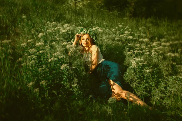 Mulher deitada na grama com grinalda na cabeça — Fotografia de Stock