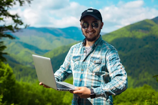 Man in zonnebril en met een laptop in handen — Stockfoto