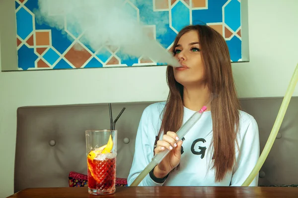 Brunette woman with green eyes smokes shisha — Stock Photo, Image