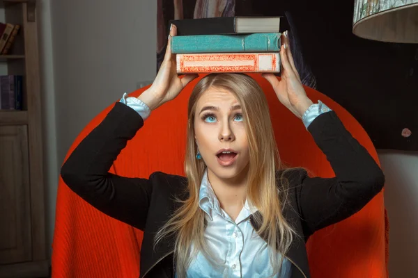 Blond meisje met boeken over haar hoofd — Stockfoto