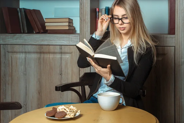 Bella ragazza a tavola con una tazza di caffè con un libro in — Foto Stock