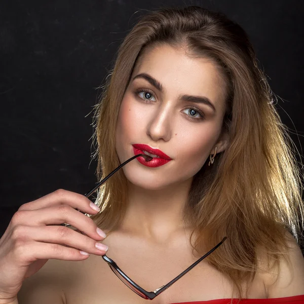 Bella donna con labbra rosse e occhiali in bocca — Foto Stock