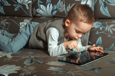 Çocuk şık elbiseli bir koltukta yalan