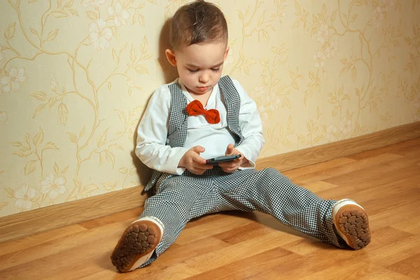 Мальчик с бабочкой играет на мобильном телефоне — стоковое фото