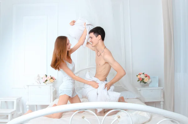 Casal alegre em uma cama branca — Fotografia de Stock