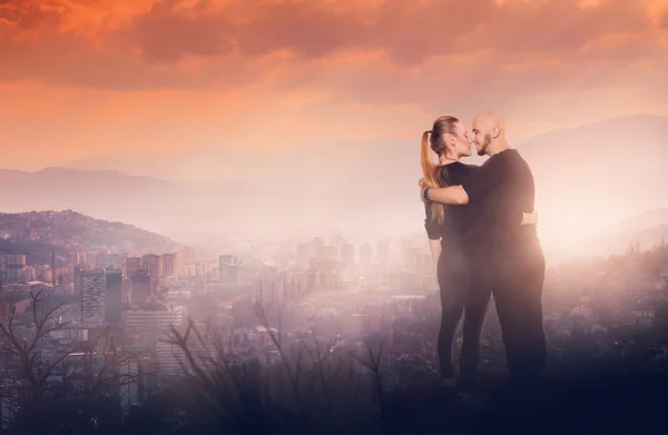 Vrolijke paar op een hoge heuvel met uitzicht op de stad — Stockfoto
