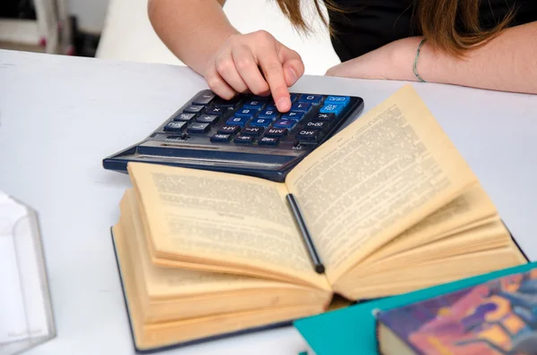 Жіноча рука з калькулятором і книгою — стокове фото