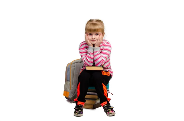 Little girl sits on a pile of books — Stock Photo, Image