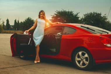 kırmızı araba yakınındaki gün batımında genç kadın