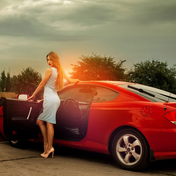 Schlanke junge Frau steht neben rotem Sportwagen — Stockfoto